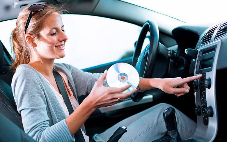 Девушка вставляет диск в аудиоплеер автомобиля